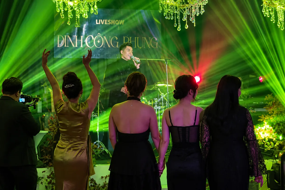 Đinh Công Phụng performing beneath green lights as the audience sings along