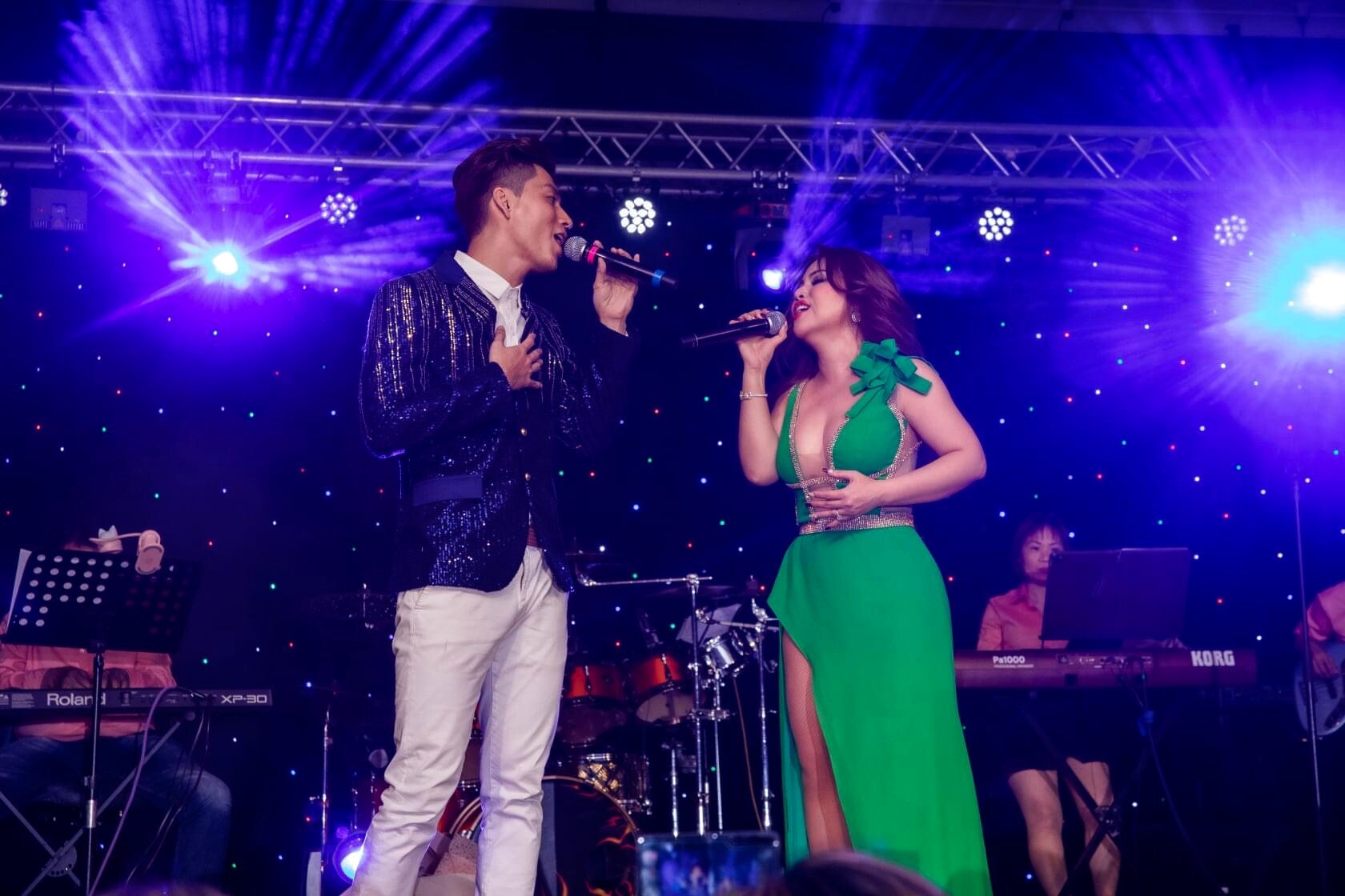 Đinh Công Phụng singing a duet beneath violet stage lights